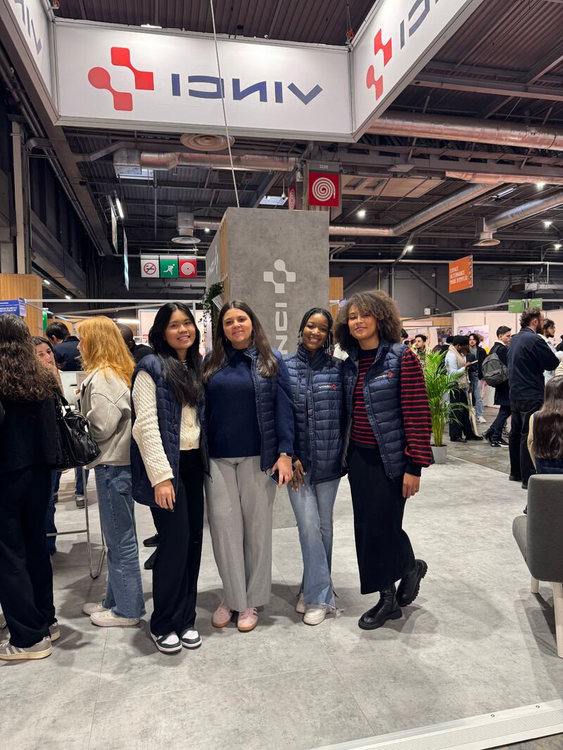 Quatre personnes en gilet bleu marine devant le stand VINCI au Salon de l'Apprentissage